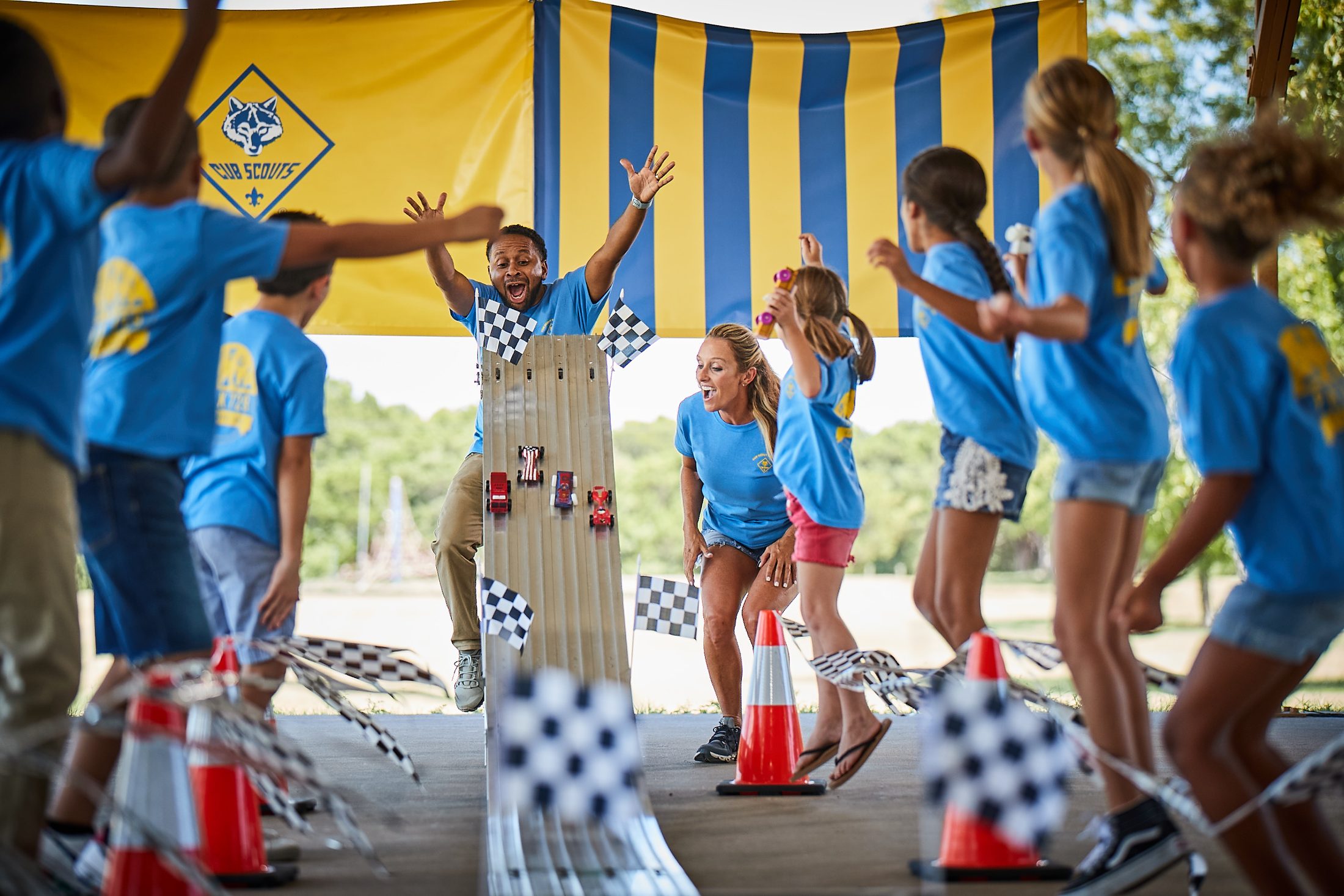Cub Scouts and adult leaders cheering at a Pinewood Derby finish line