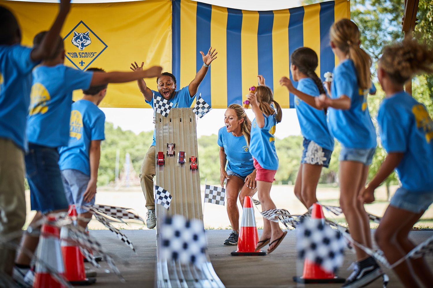 Cub Scouts and adult leaders cheering at a Pinewood Derby finish line